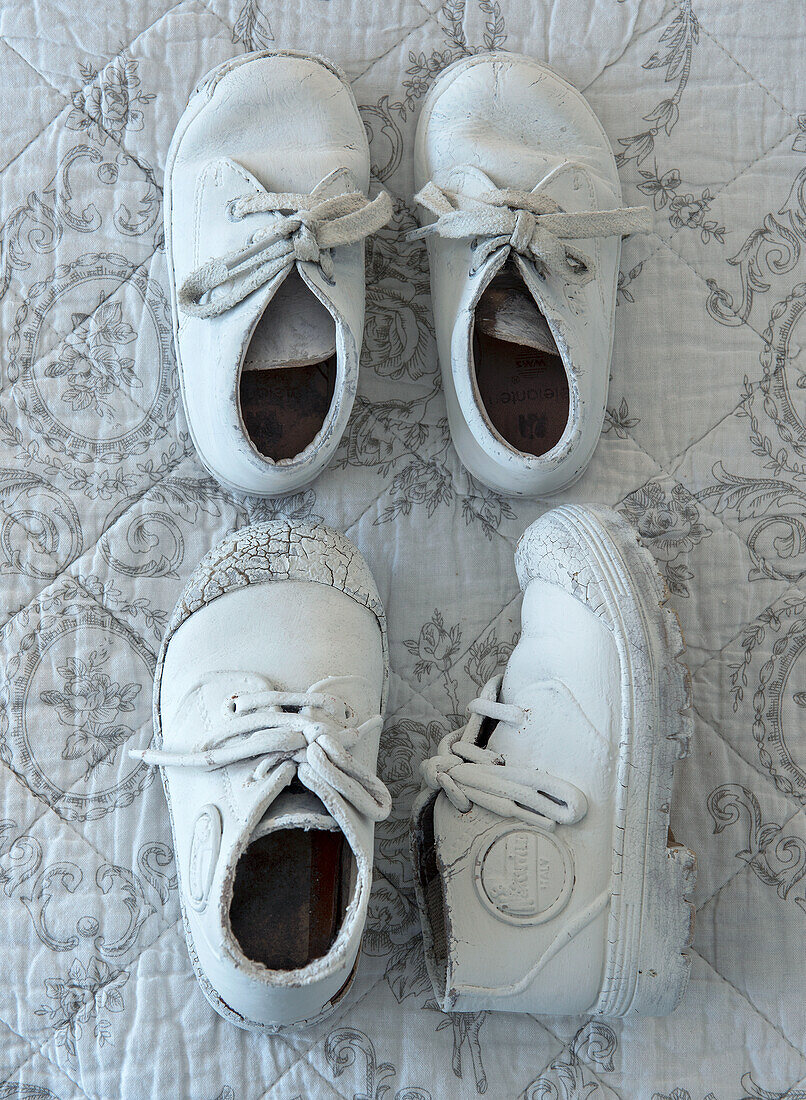 White, worn children's shoes on an embroidered fabric base