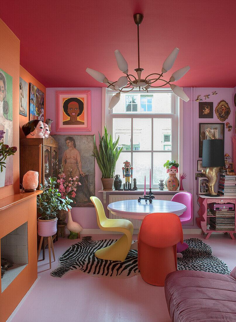 Colourful dining room with fireplace, vintage art and Panton chairs