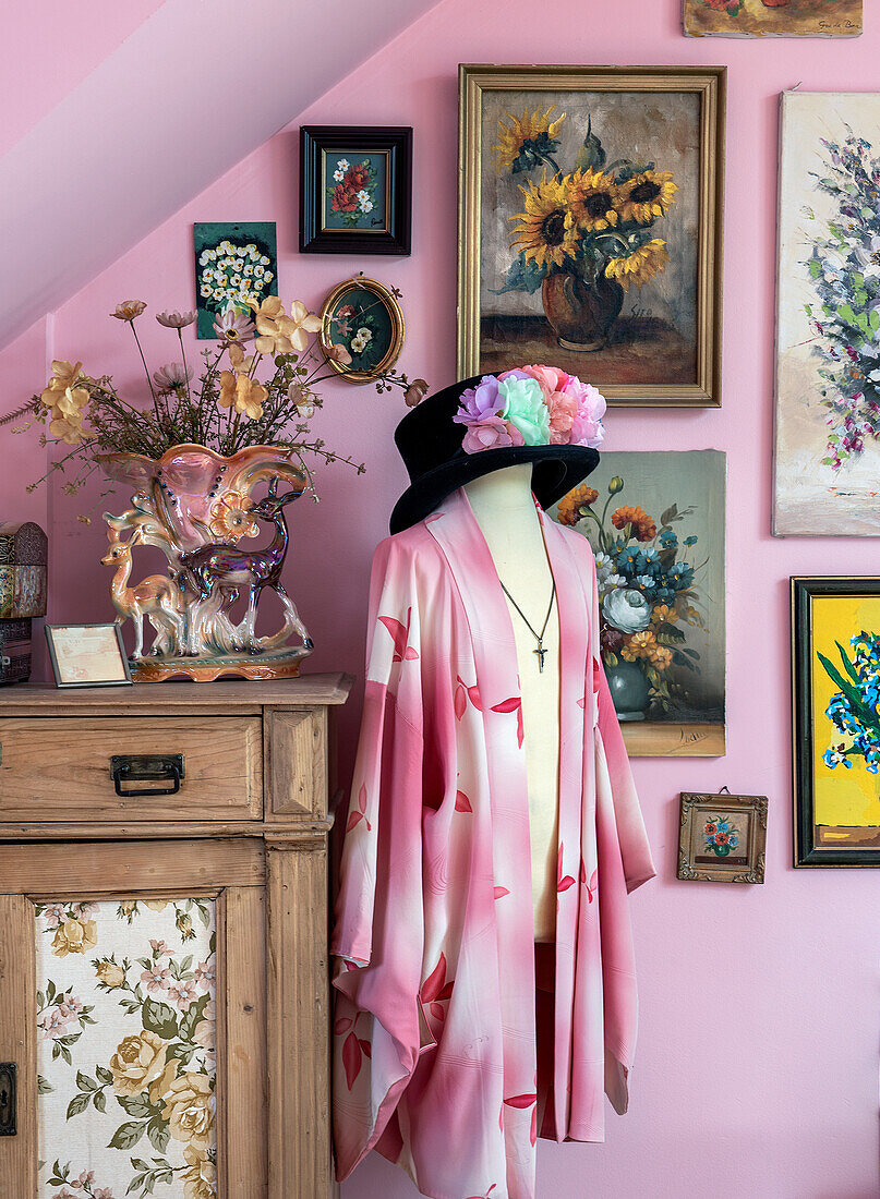 Wanddekoration mit Blumenbildern, rosa Kimono und Vintage-Dekorationsstücken