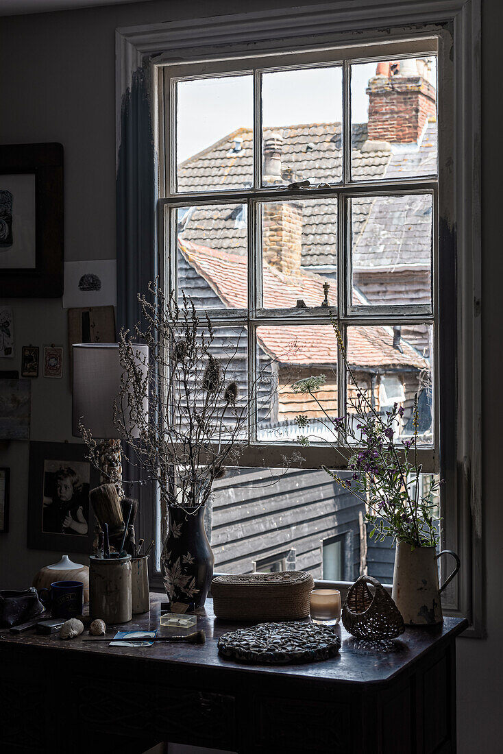 Desk with dried branches and view of neighbouring rooftops