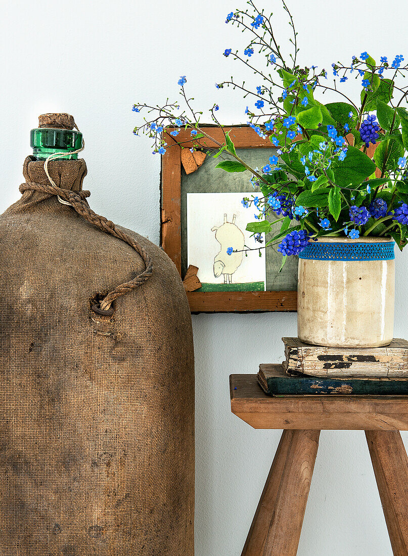 Forget-me-nots (myosotis) in a rustic vase on a wooden table with antique books