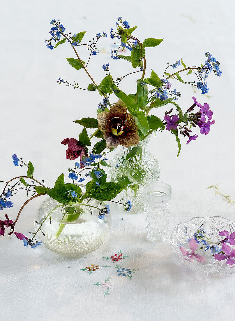 Vasen mit Frühlingsblumen auf bestickter Tischdecke