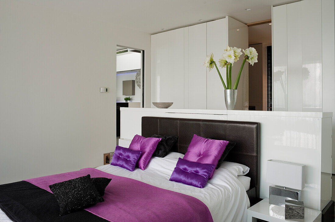 Bedroom with double bed with purple colour accents and white wardrobes