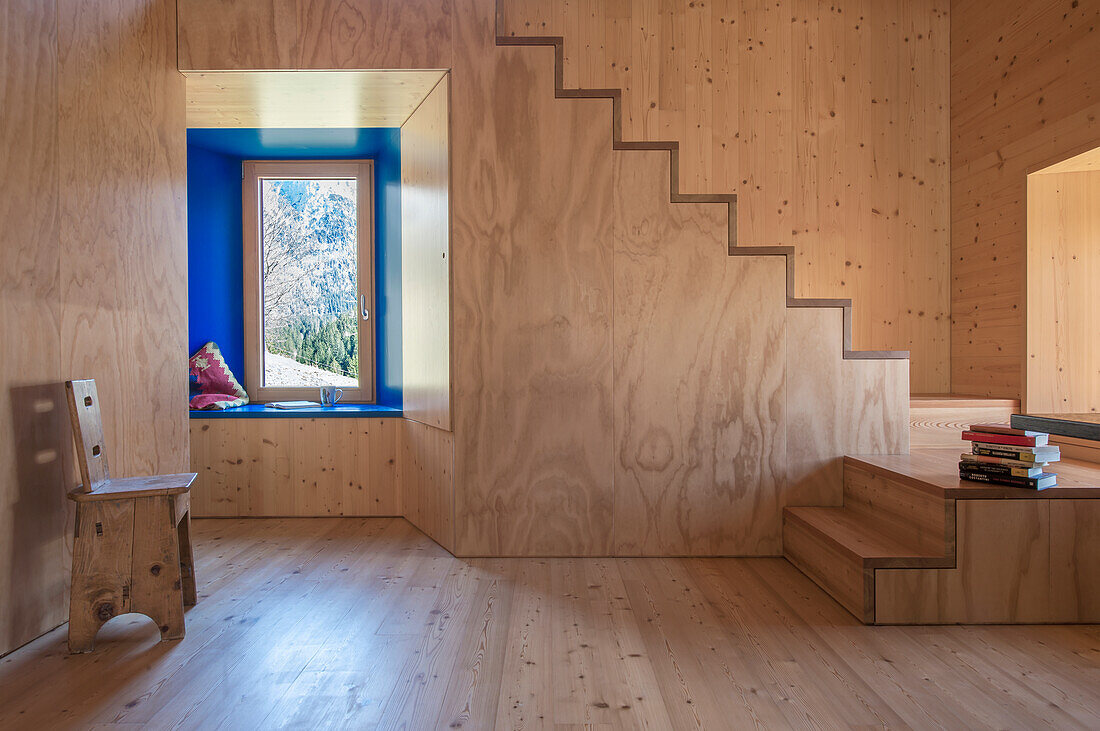 Helles Zimmer mit Holzvertäfelung und eingelassener Fensternische, Holztreppe