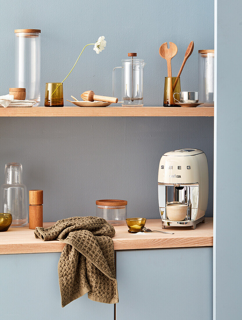 Kitchen in soft light blue with wooden kitchen shelf, coffee machine and kitchen utensils on top