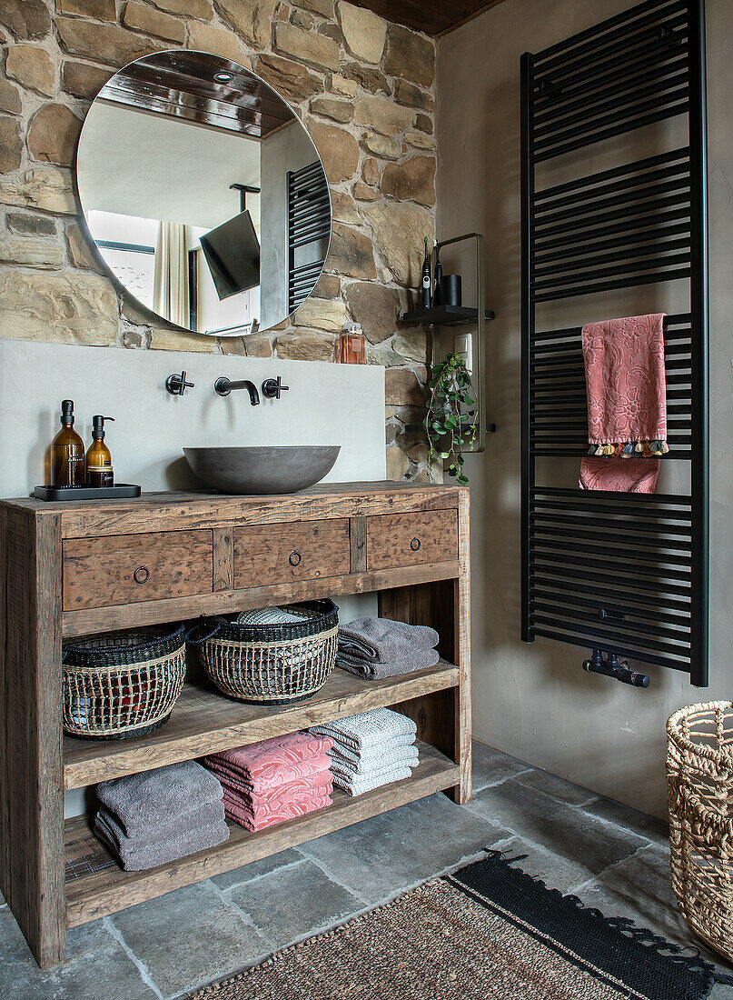 Rustic bathroom with wooden washbasin and round mirror