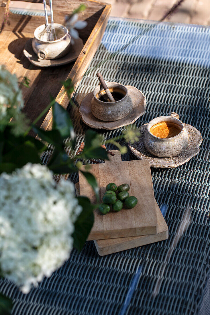 Holztablett mit Tassen und Schneidebrett auf Gartentisch aus Rattan