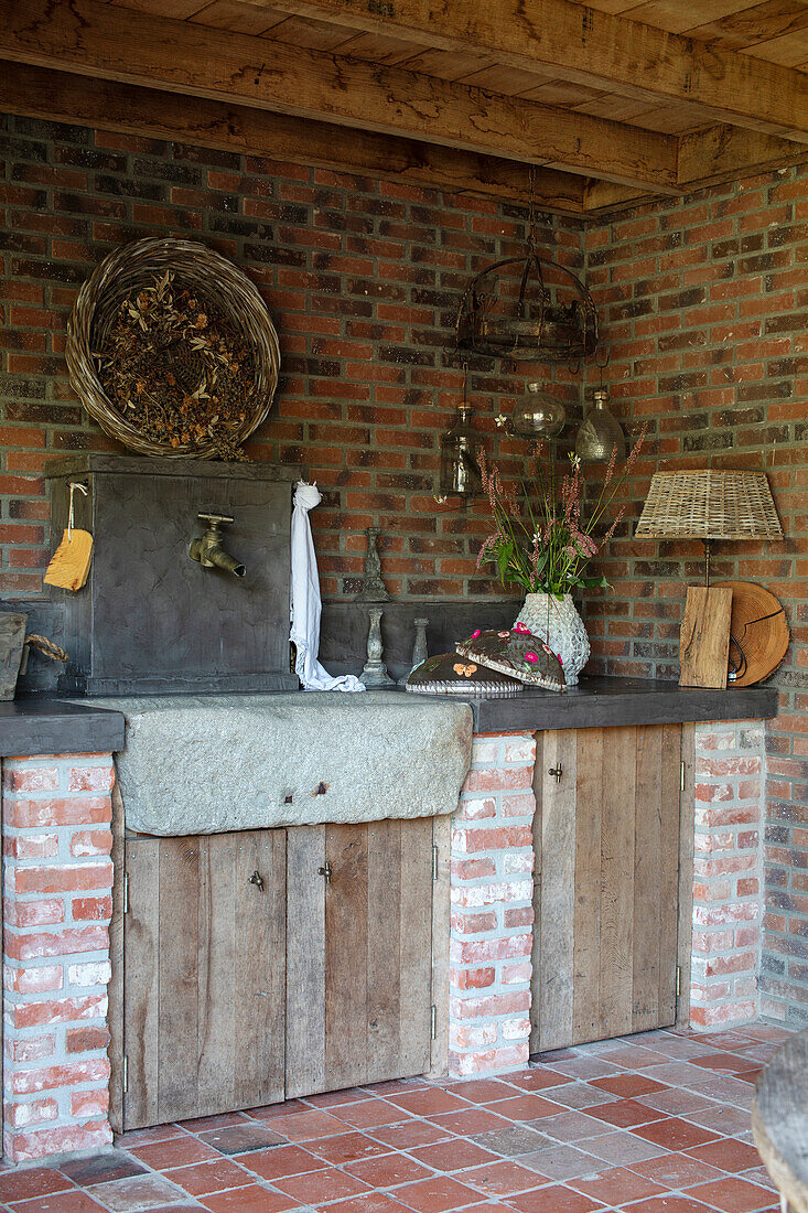 Rustic outdoor kitchen with stone sink and brick walls