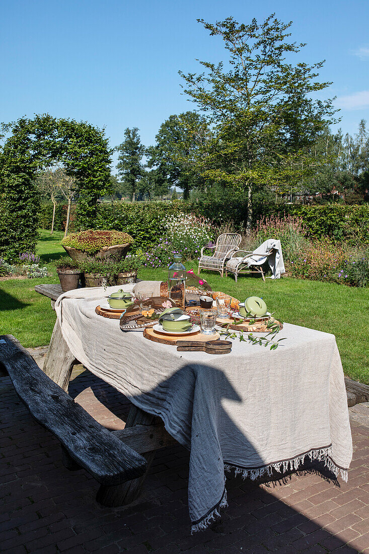 Set garden table with rustic wooden bench in the lush garden