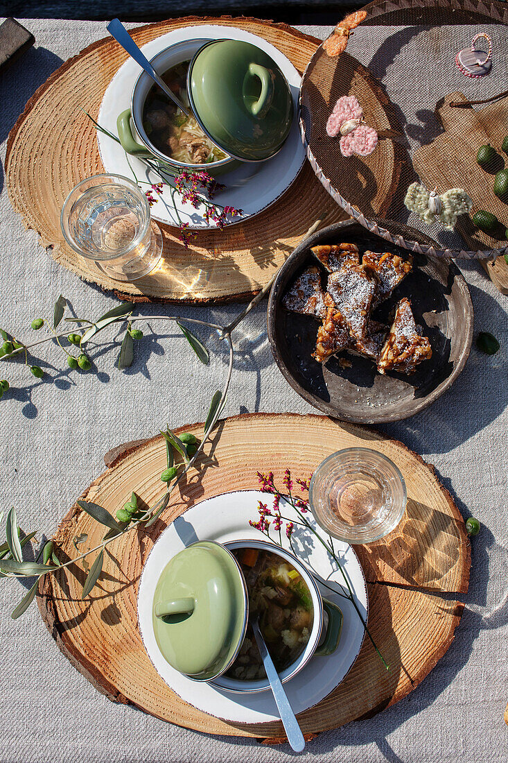 Platzset aus rustikalen Holzscheiben, mit grünen Suppenschalen und Deckel