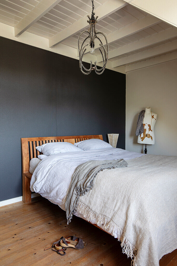 Wooden bed in bedroom with grey accent wall