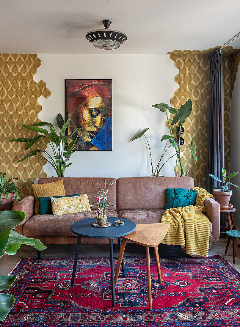 Living room with brown leather sofa, exotic plants and colourful carpet