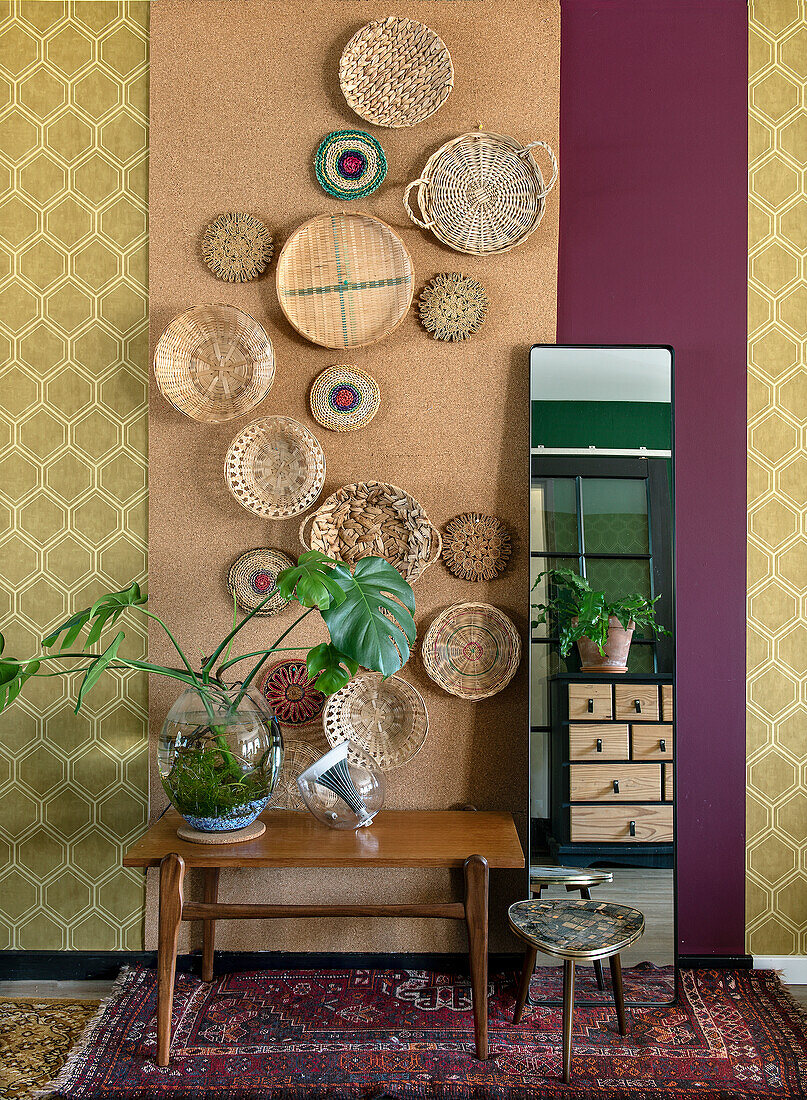 Cork wall with woven baskets, wooden bench, houseplants and mirror in the living room