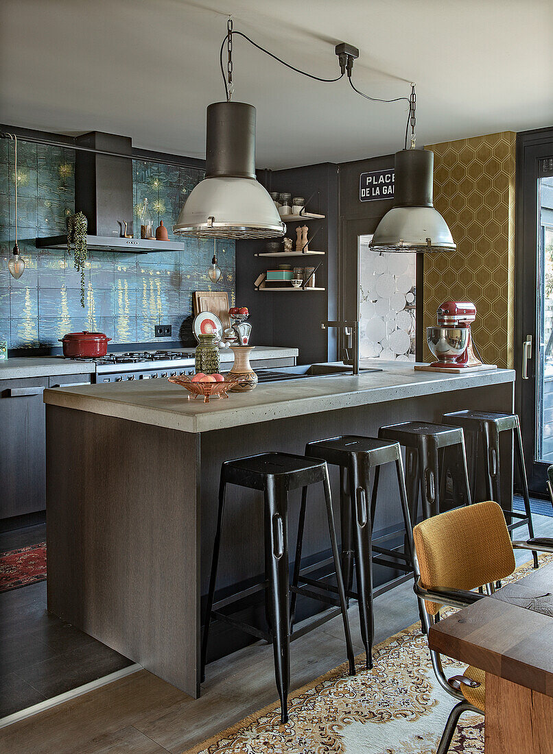 Modern kitchen with dark island, black bar stools and hanging industrial lamps