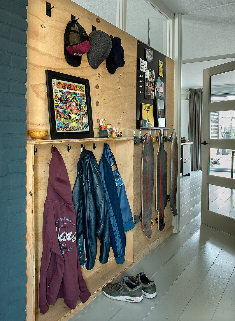 Garderobenwand aus Sperrholz mit Skateboards, Jacken und Caps im Flur