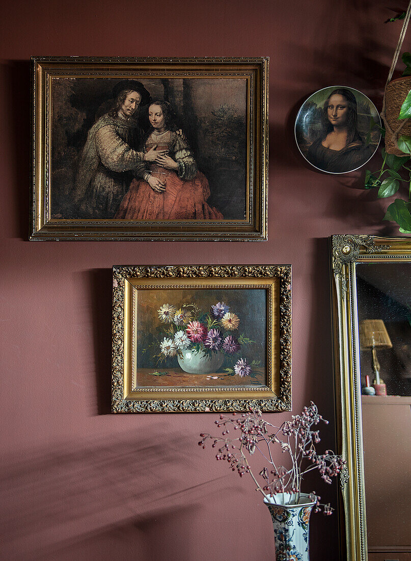 Gallery wall with classic paintings and mirror in front of red wall