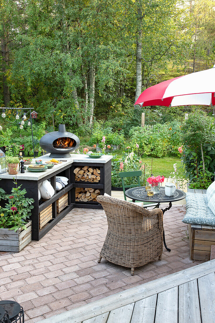 Gemütliche Terrasse mit Outdoor-Küche, Rattanmöbeln und großem Gartenbereich