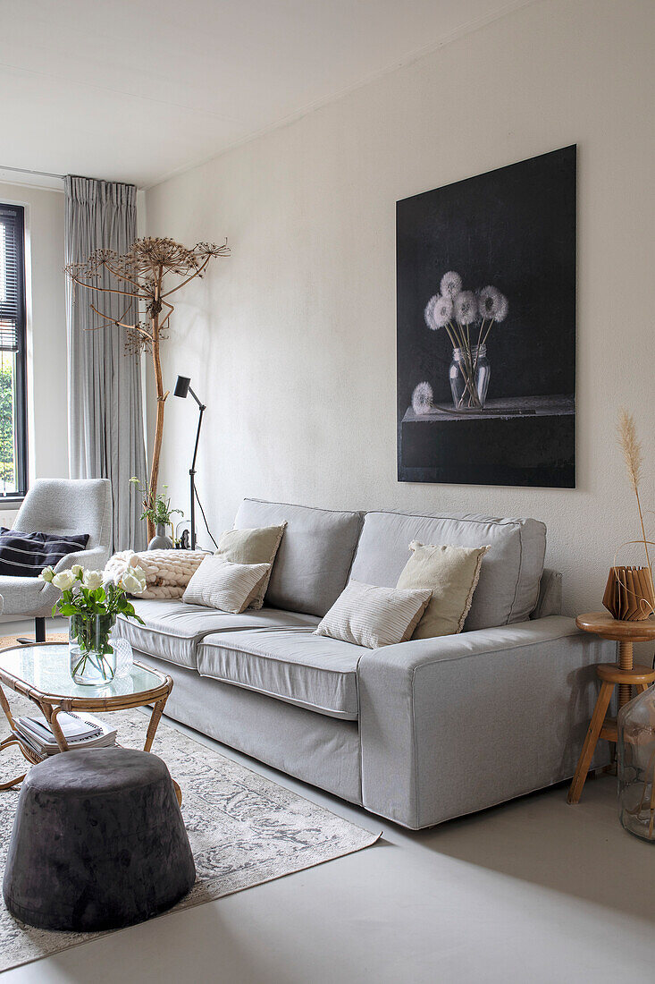 Bright living room with light grey sofa and large flower painting on the wall