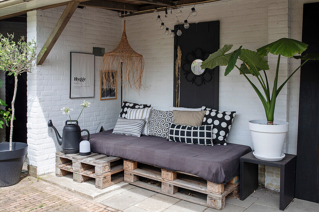 Cozy patio area with pallet sofa and large potted plants