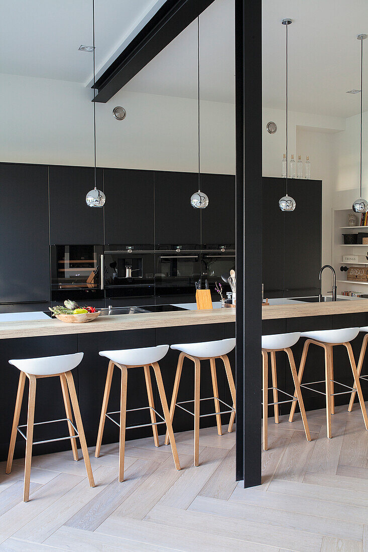 Modern kitchen with black high-gloss fronts and white bar stools