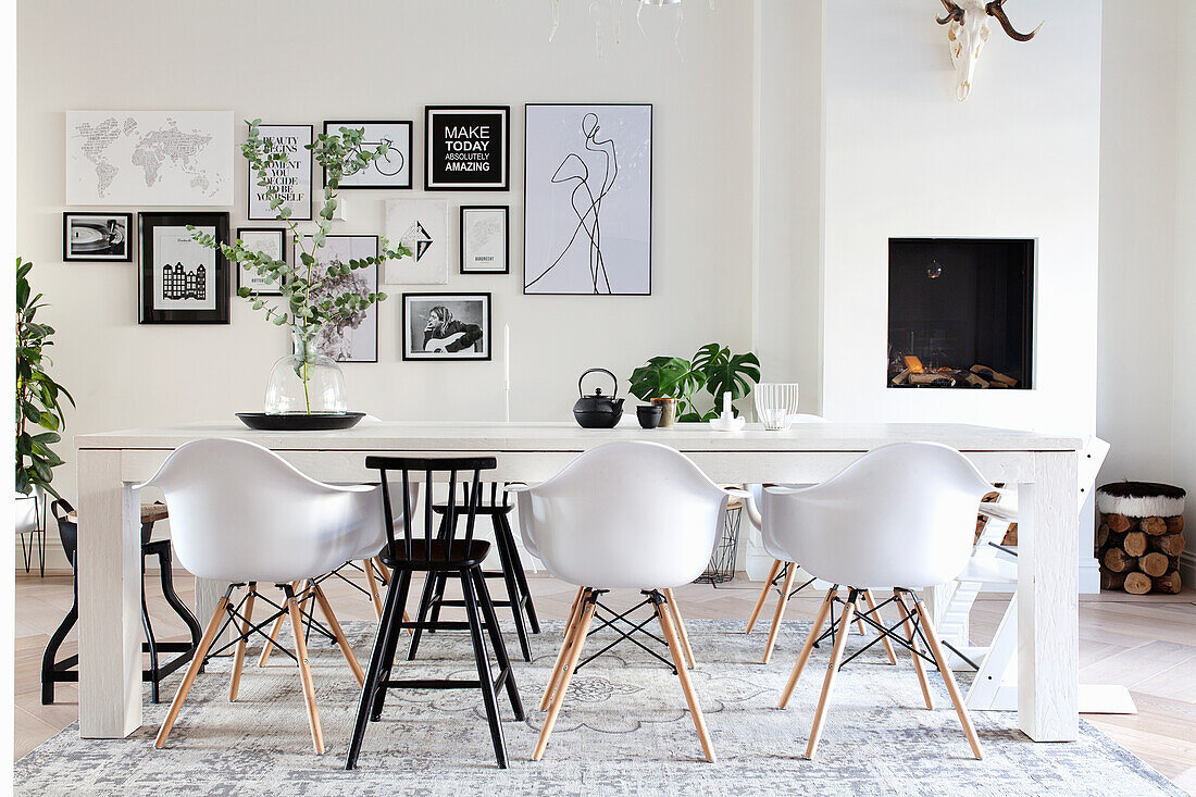 Dining room with white wooden table, Eames chairs and picture gallery on the wall