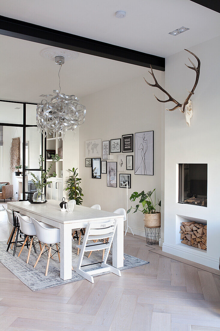 Dining room with white wooden table, designer lamp and wall art gallery