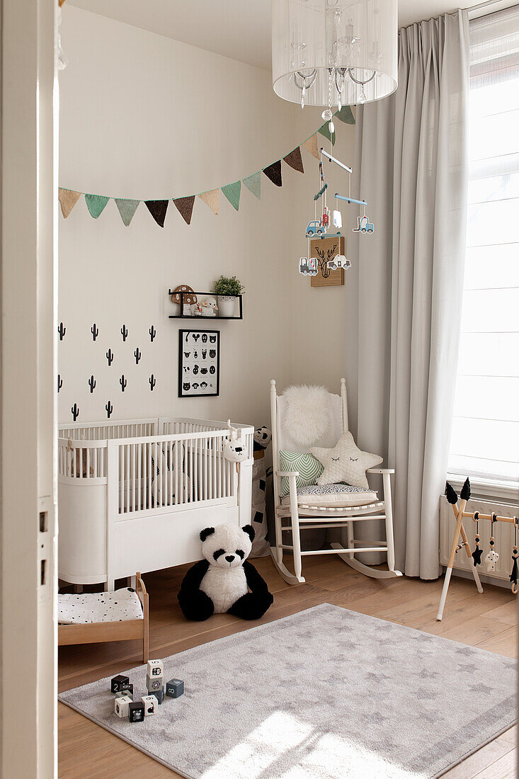 Bright children's room with cot, toys and bunting garland