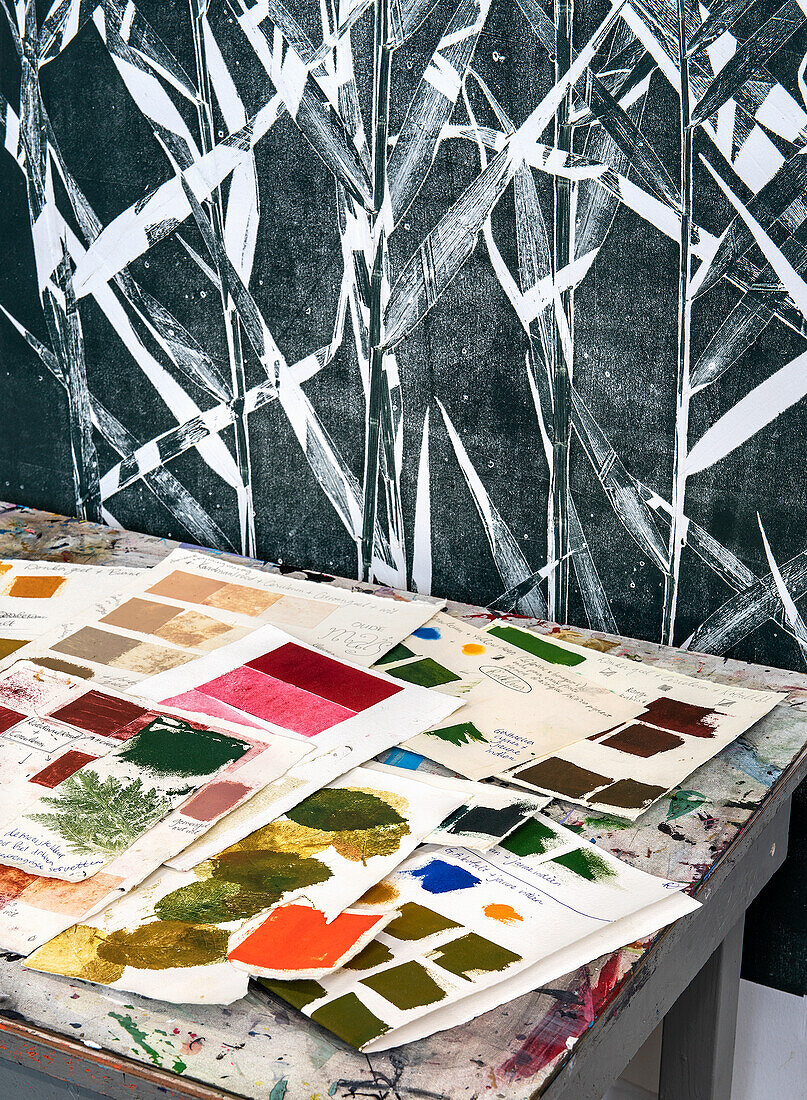 Artistic workspace with color samples, prints and leaf pattern wall