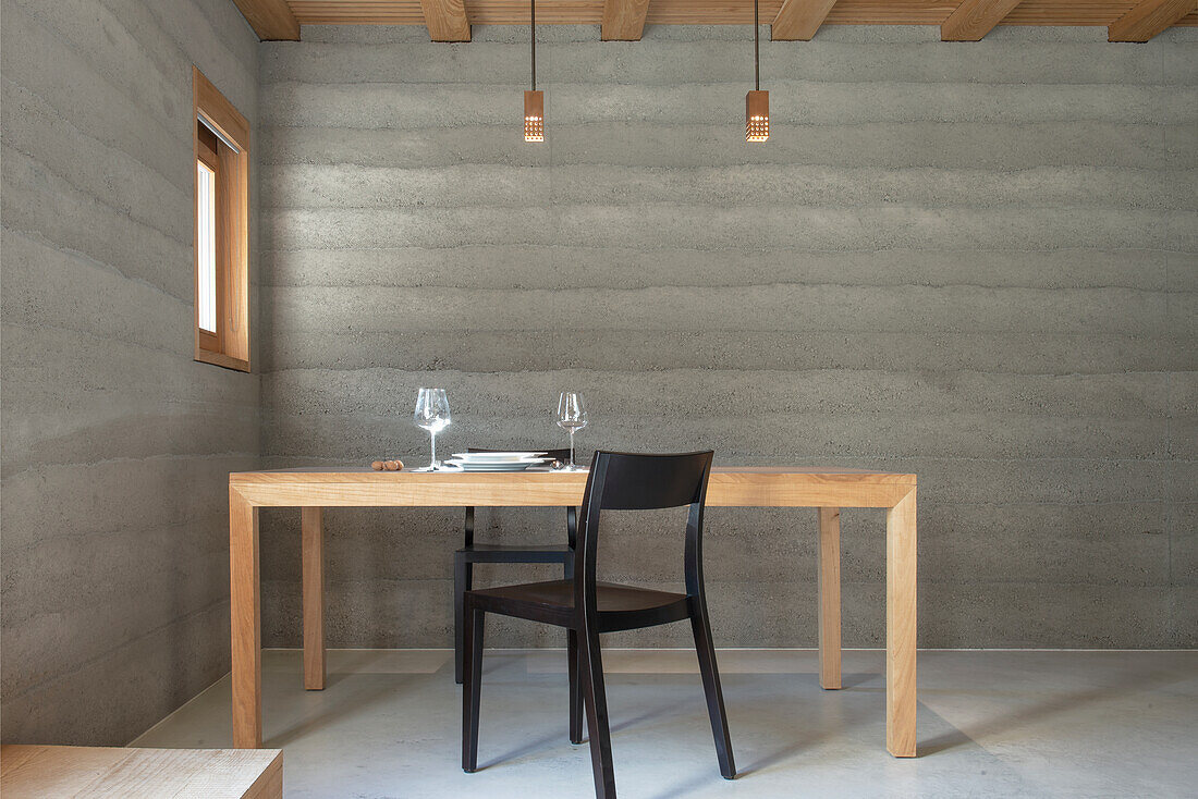 Minimalist dining area with concrete wall and wooden furniture