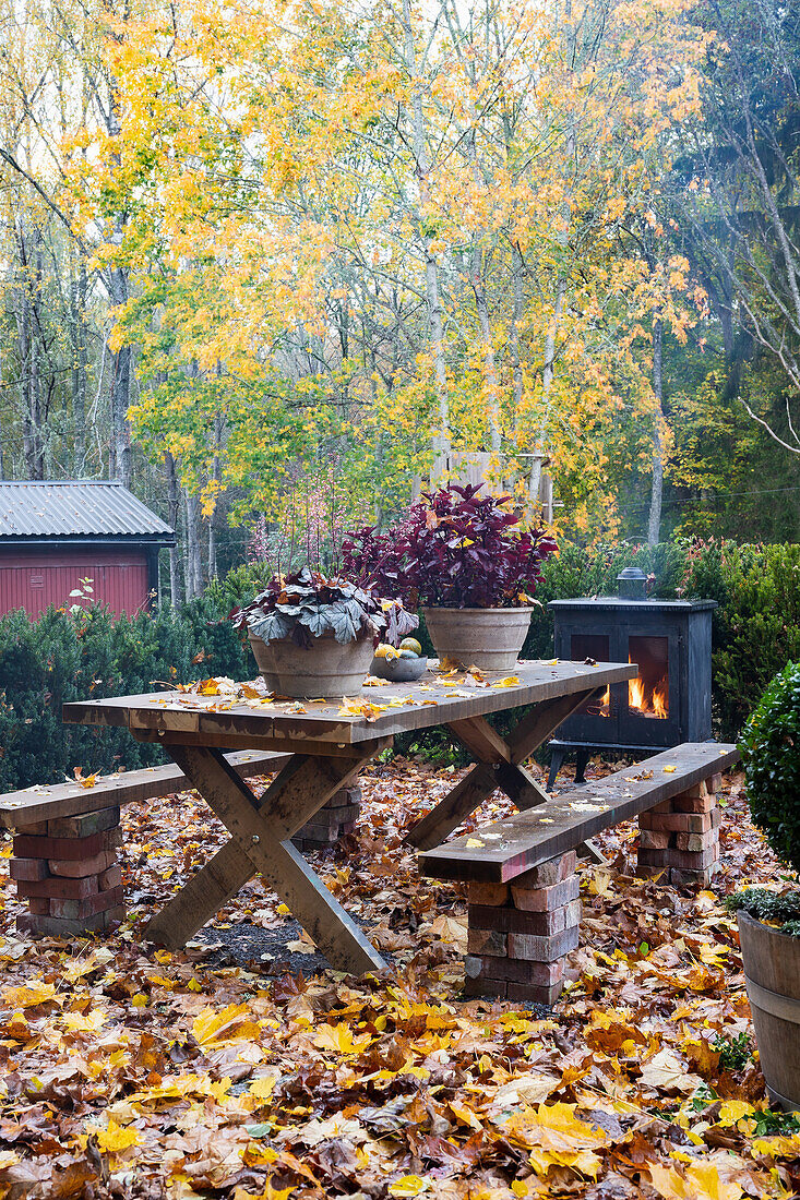 Autumnal patio table and outdoor fireplace surrounded by foliage