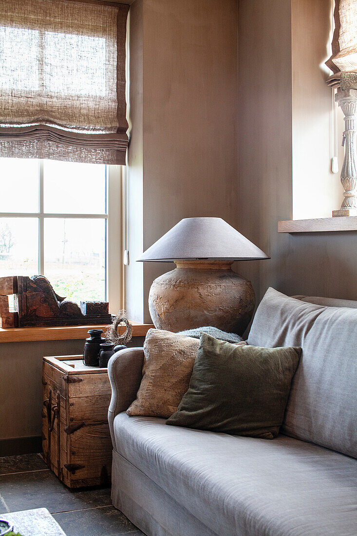 Hellgraues Sofa mit Kissen und rustikaler Lampe im Wohnzimmer