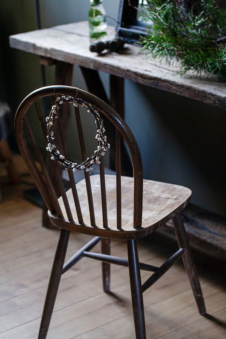 Old wooden chair with wicker wreath in front of rustic wooden table