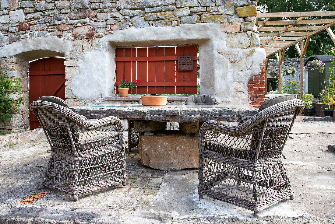 Rustikaler Steintisch mit Rattanstühlen auf Terrasse