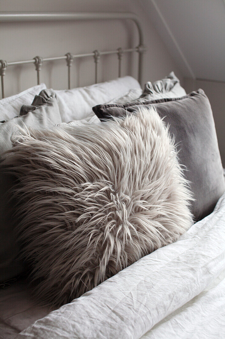 Fluffy faux fur cushion on a metal bed in the bedroom