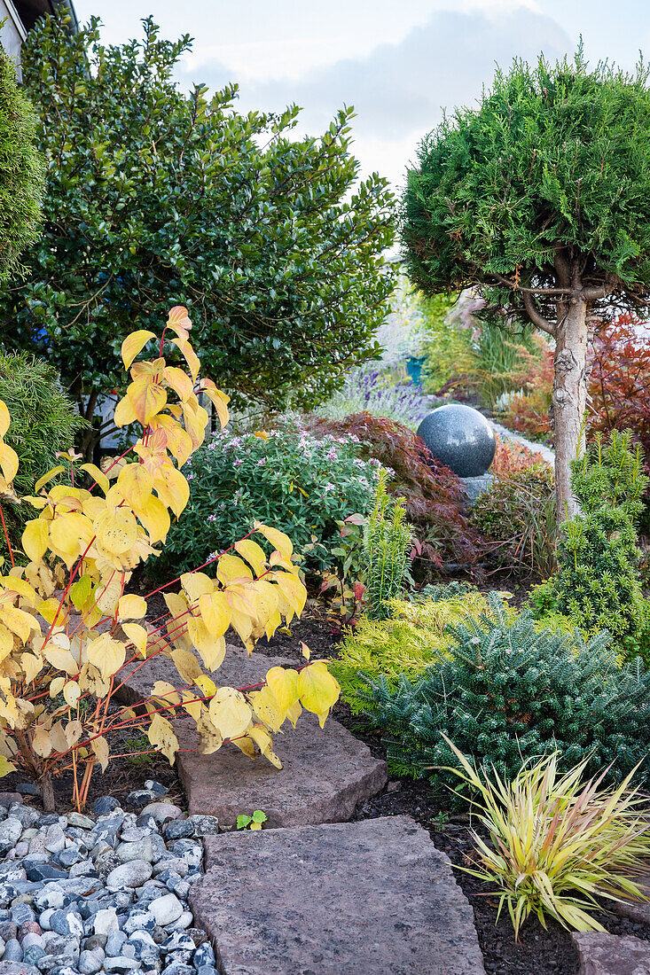 Diverse autumn garden with decorative stone ball