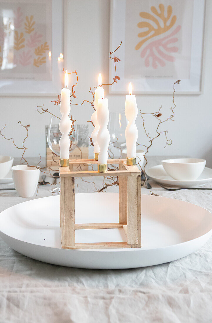 Wooden candle holder with twisted candles on a laid table