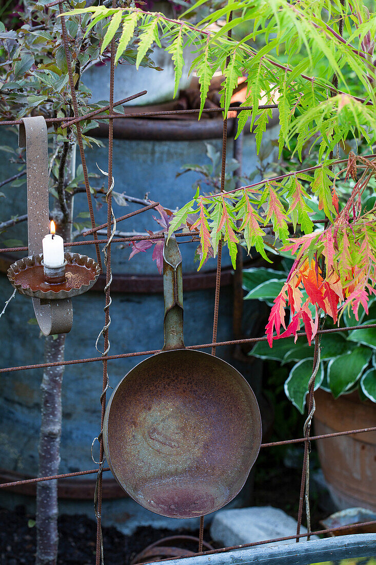 Rustic garden decoration with old pans and candle holders on an iron grid