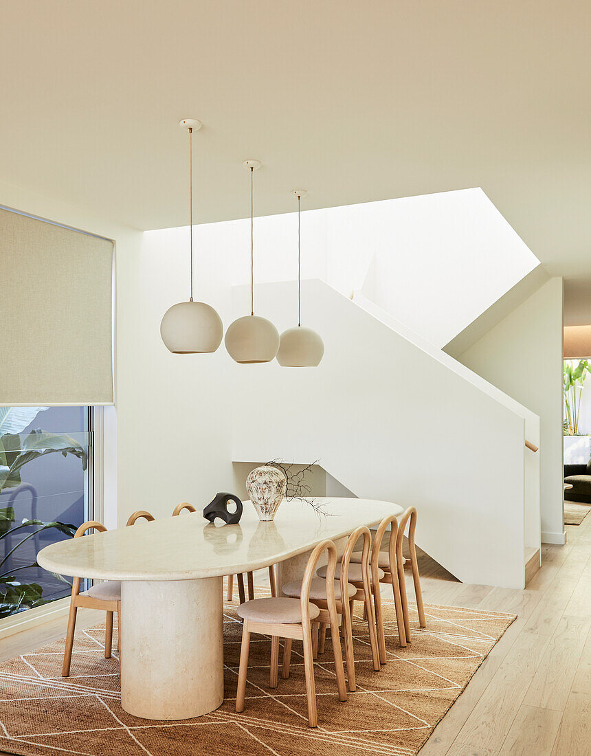 Dining room with oval marble table and modern staircase