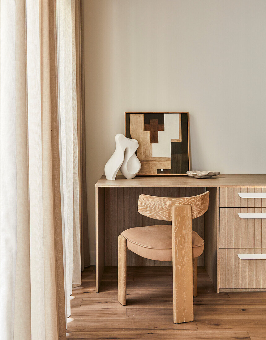 Minimalist workspace with designer wooden chair and abstract art