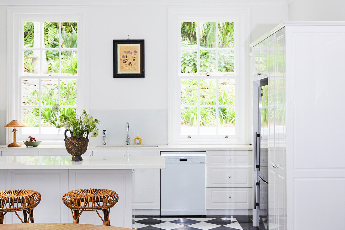 White kitchen with rattan bar stools and chequerboard floor