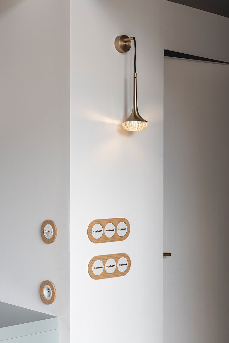 Modern metal wall light with glass element on a white wall