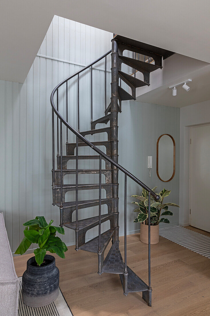 Metal spiral staircase in a modern living room with green plants