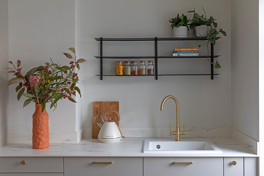 Modern kitchen unit with golden fittings and plant decoration