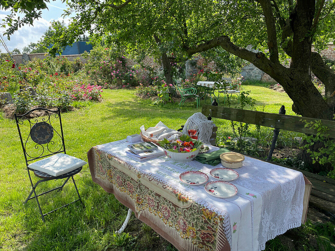 Gedeckter Tisch im Garten mit Tischdecke aus Spitze und Geschirr