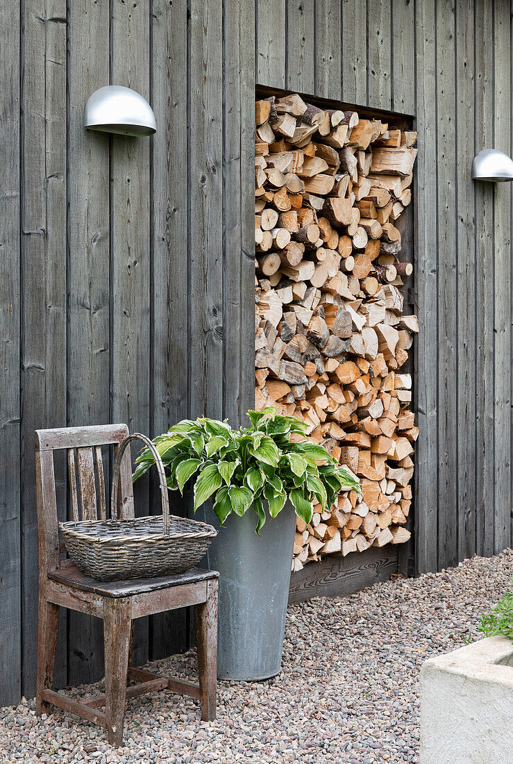 Gartenbereich mit Holzlager, Holzstuhl und Pflanze