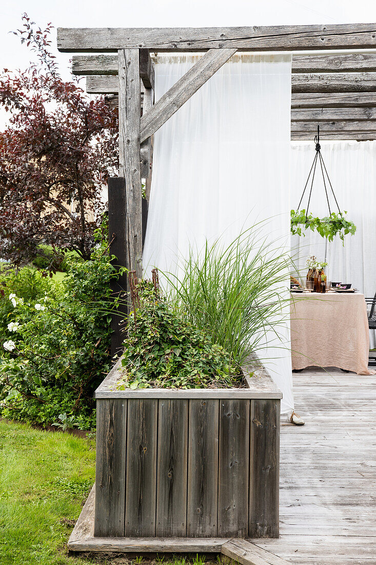 Wooden terrace with rustic pergola and raised bed