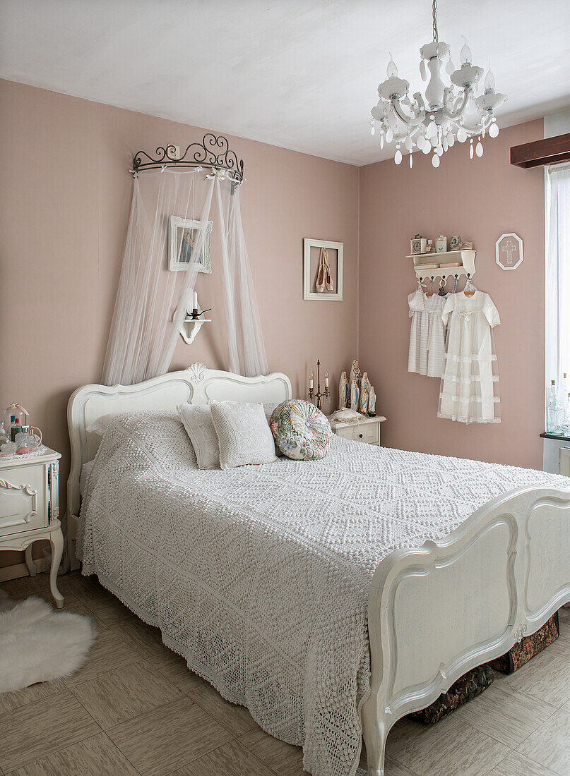 Romantic bedroom with bed canopy and chandelier in shades of pink and white