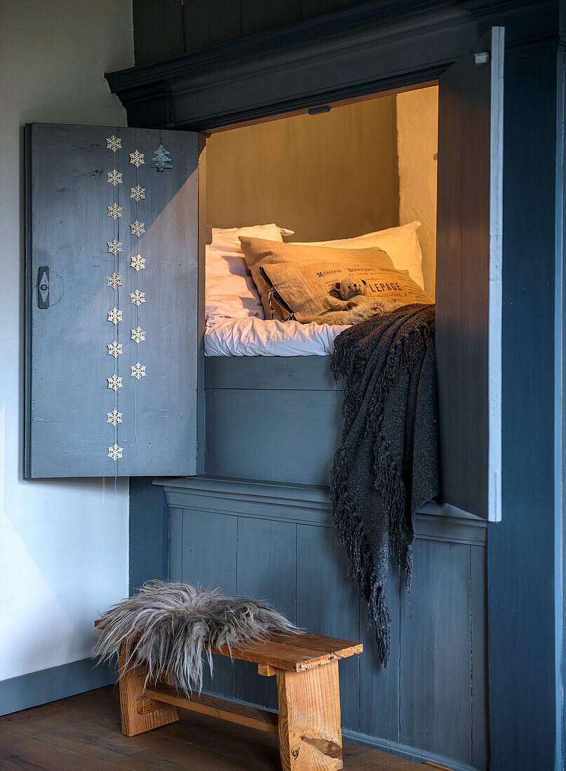 Alcove bed and rustic wooden stool with fur