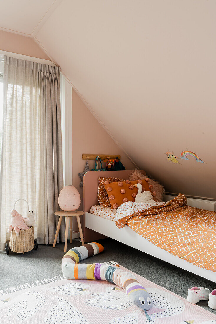 Kinderzimmer mit Bett unter Dachschräge und Kuscheltieren