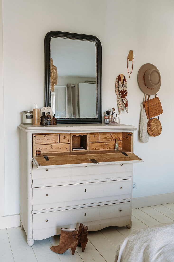 Chest of drawers with mirror in bedroom, boots on the floor